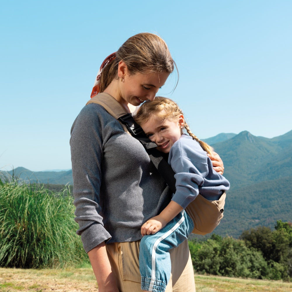 Ergonomische Jané Catch Hüfttrage in Beige im Bergurlaub Mutter mit ihrer Tochter