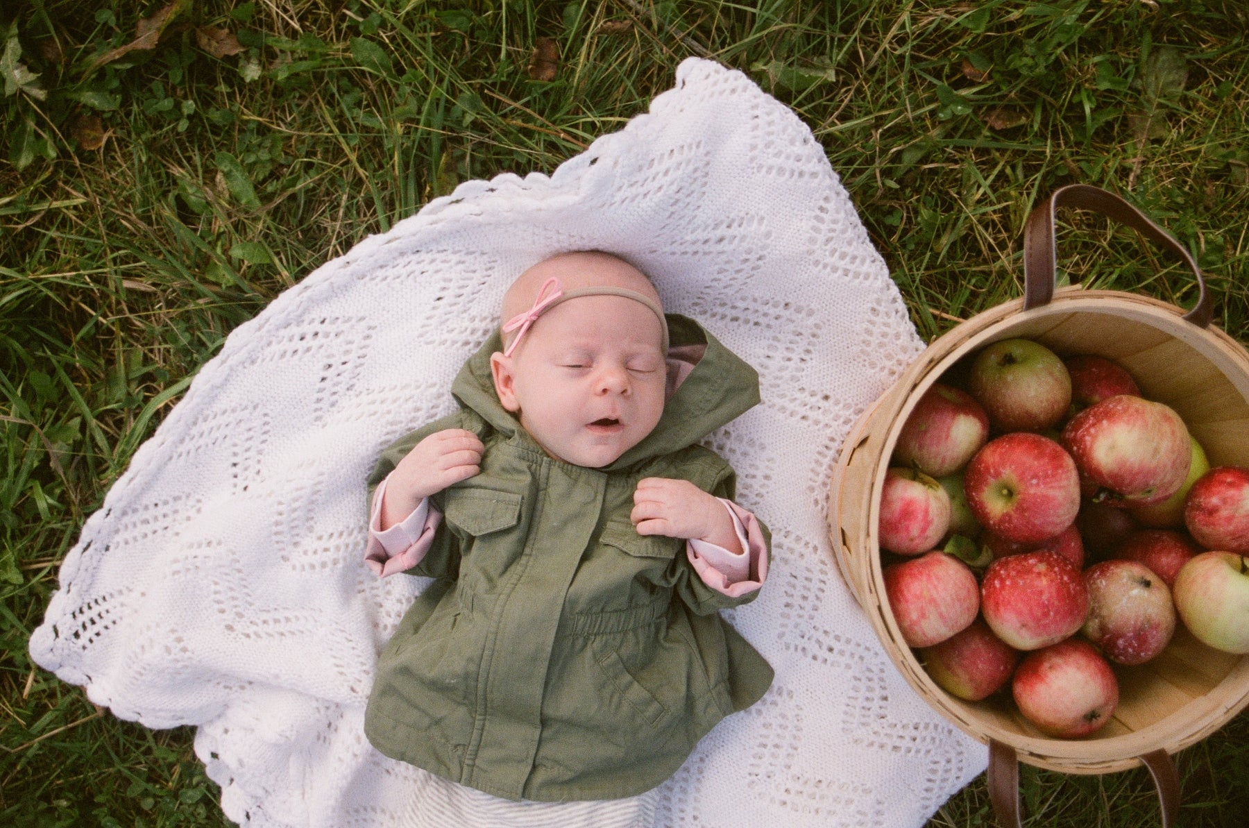 baby-liegt-schlafen-auf-einer-decke-neben-einem-Apfelkorb